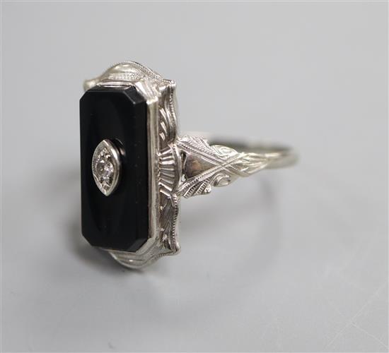 A 10k white metal, black onyx and diamond set shaped rectangular ring, size L.